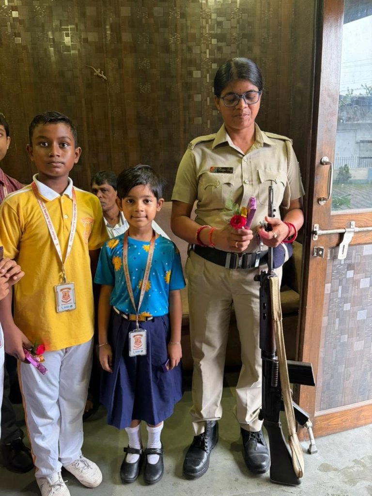 Two students of the school standing with a police officer during a community outreach visit