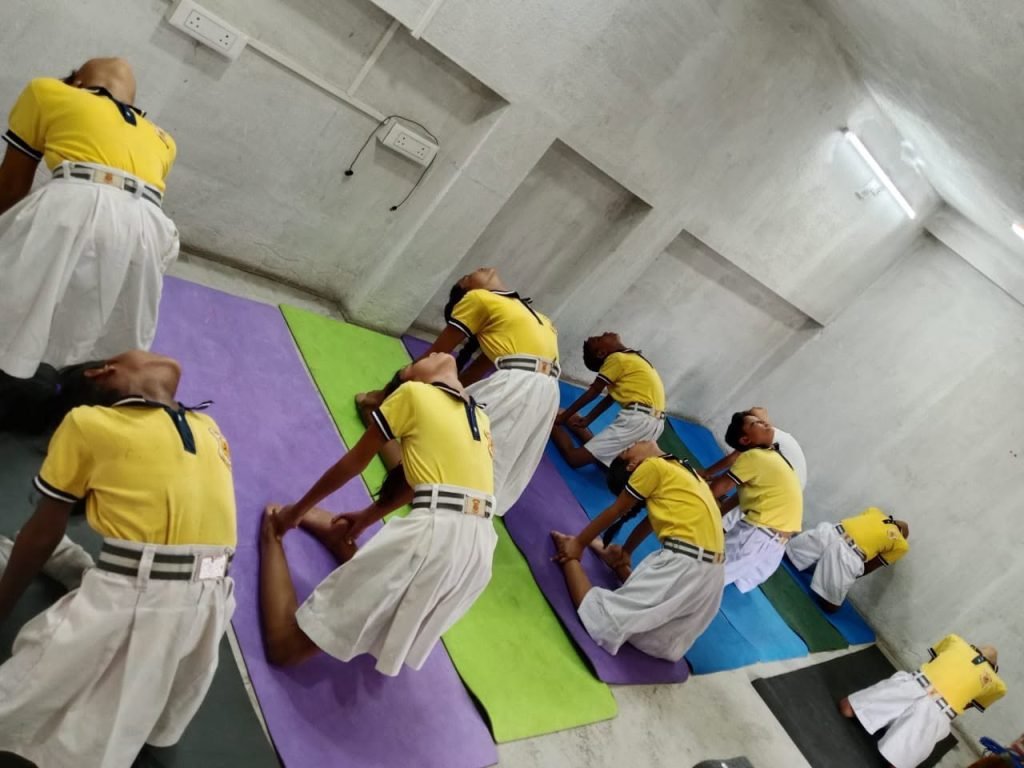 A yoga class in progress with students stretching on coloured mats