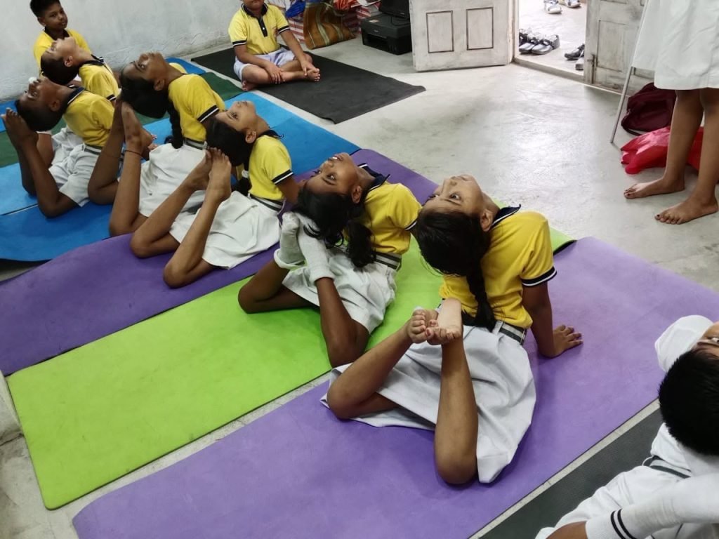 Students practising yoga together on mats in the school hall